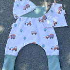 Vue de dessus de l’ensemble naissance motif chantier – bonnet, bavoir et sarouel bébé faits main