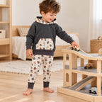 Garçon de trois ans jouant avec un garage en bois, vêtu d’un sweat anthracite et d’un legging écru à chats, bords dépliés.