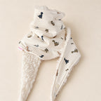Foulard enfant écru à motifs de dinosaures à long cou et de palmiers, avec doublure blanche, présenté sur fond crème.