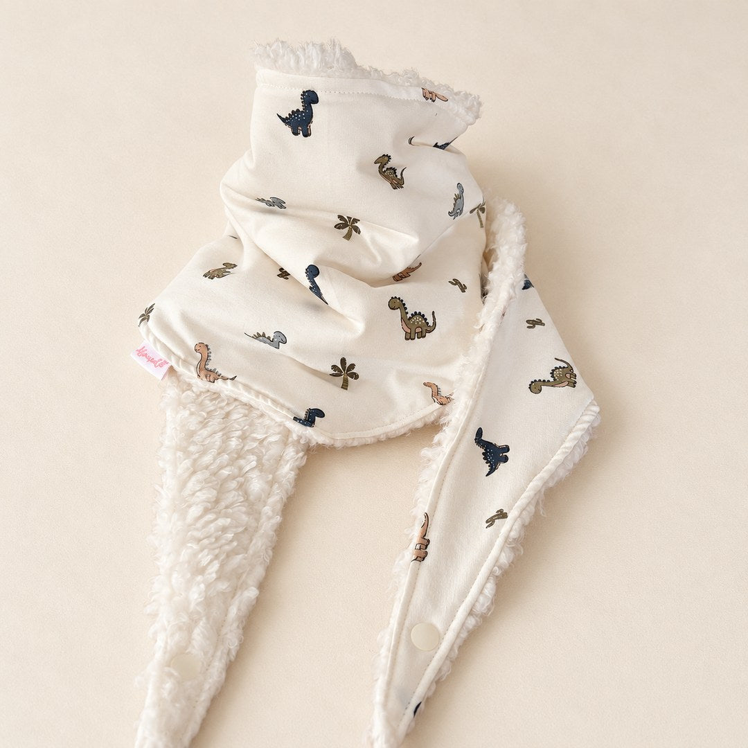 Foulard enfant écru à motifs de dinosaures à long cou et de palmiers, avec doublure blanche, présenté sur fond crème.