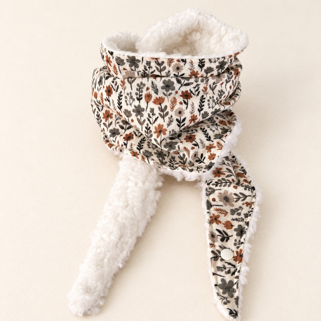 Foulard enfant écru à petites fleurs noires, taupe et rouille, avec doublure blanche et deux pans ouverts, présenté sur fond crème.