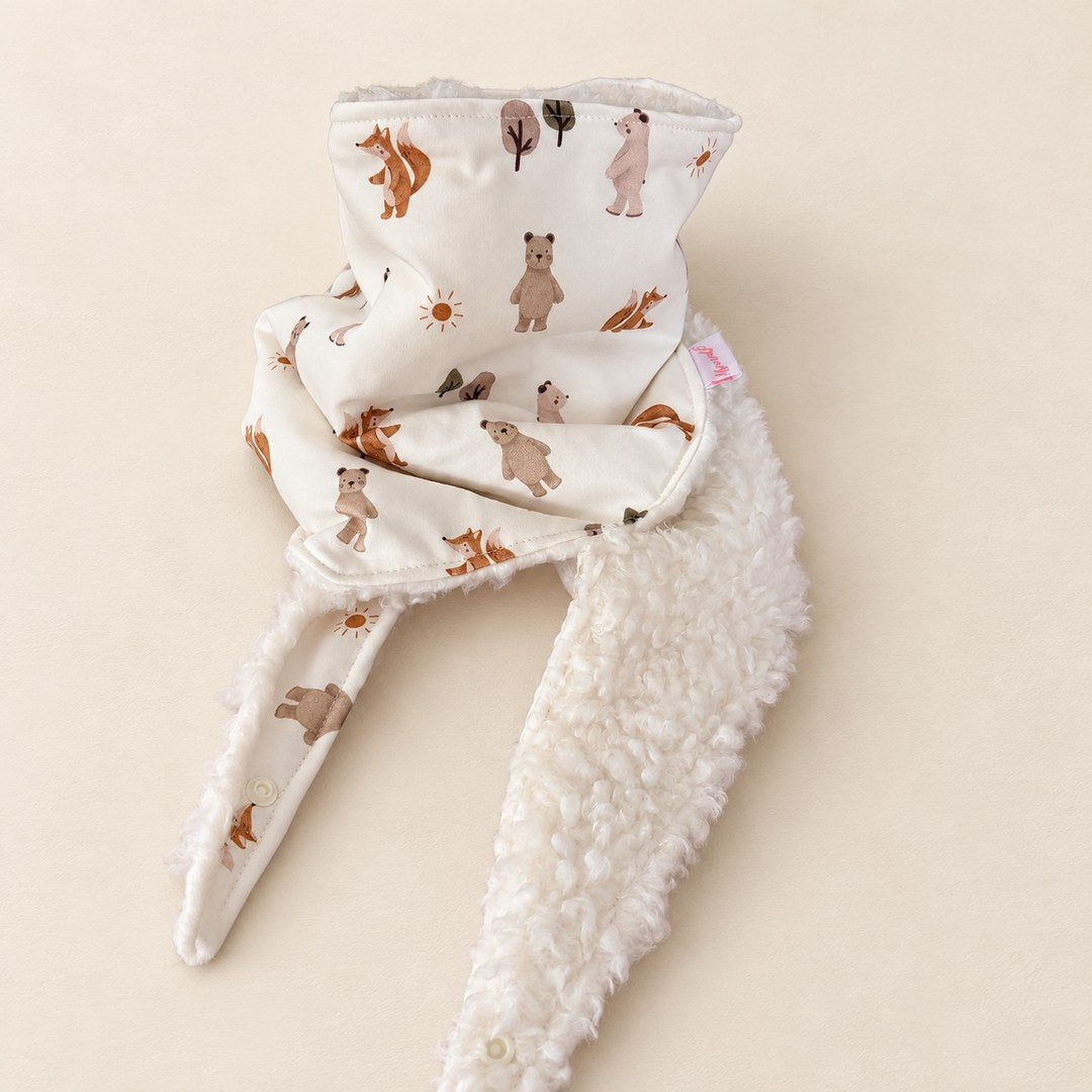 Foulard enfant écru à motifs d’ours, d’écureuils et d’arbres, avec doublure blanche et deux pans ouverts, présenté sur fond crème.
