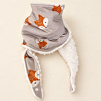 Foulard enfant taupe à motifs de grandes têtes de renards orange, avec doublure blanche, présenté sur fond crème.