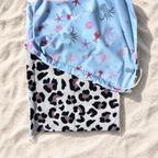 Pare-soleil pour poussette avec motif océan bleu et tissu léopard beige posé sur du sable blanc