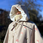 Détail capuche du poncho de pluie enfant imprimé champignons : capuche doublée minky blanc avec lien à nouer.