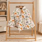 Poncho de siège auto écru à motifs de tigres, crocodiles et singes, avec capuche doublée de fourrure douce, suspendu à un portant en bois.